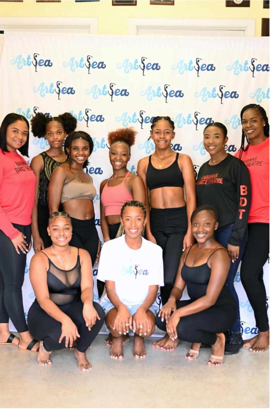 ArtSea Dance students and coaches posing together in front of an ArtSea step-and-repeat backdrop